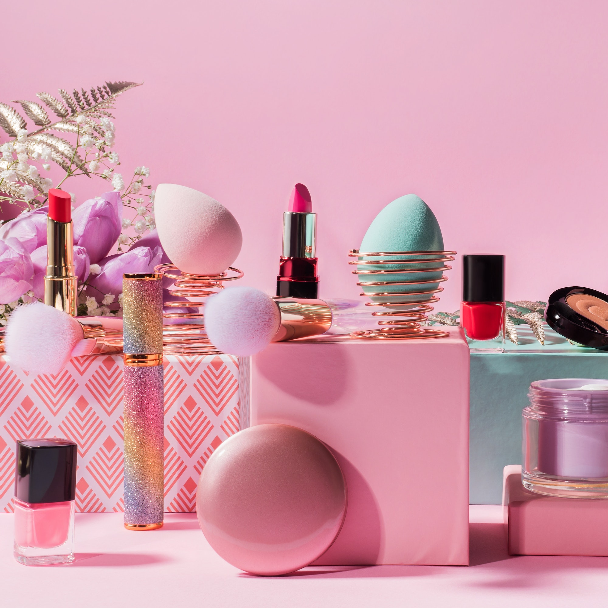 Make up tools and products on geometric podiums on pink background